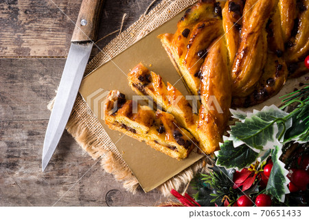 Homemade braid stuffed with chocolate and cut into pieces on wooden table. 70651433