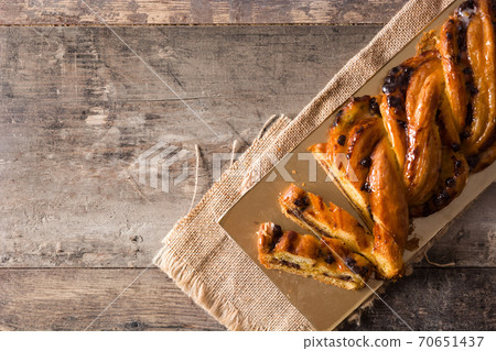 Homemade braid stuffed with chocolate and cut into pieces on wooden table. 70651437