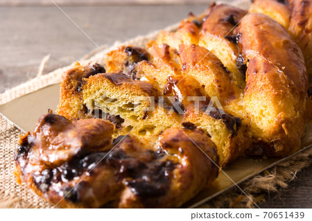 Homemade braid stuffed with chocolate and cut into pieces on wooden table. 70651439