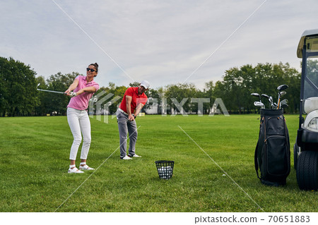 Beginner golfer and her coach training together 70651883