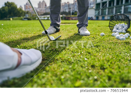 Coach instructing a beginner golfer to hit the ball Coach instructing a beginner golfer to hit the ball 70651944
