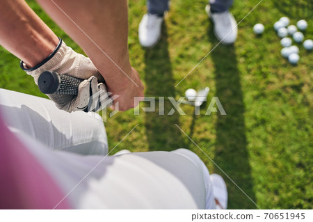 Sportswoman holding a golf putter with both hands Sportswoman holding a golf putter with both hands 70651945
