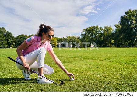 Smiling golfer in sunglasses preparing for a game 70652005