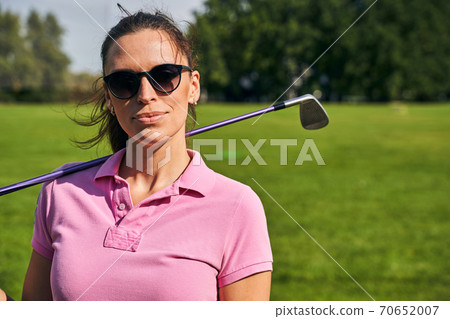 Woman with a golf club standing outside 70652007