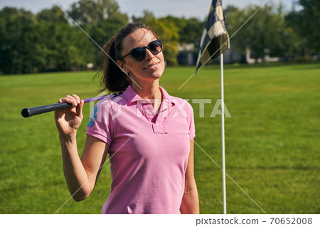 Joyous female golfer in sunglasses posing for the camera 70652008