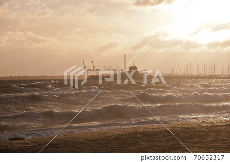 Dramatic golden light ray from the sky in the afternoon with St Kilda pier and windy ocean in Melbourne bay and high tide wave. Nobody is in the photo. 70652317