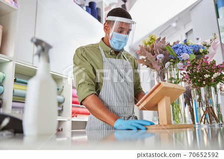 Man doing desenfection inflower shop during quarantine 70652592