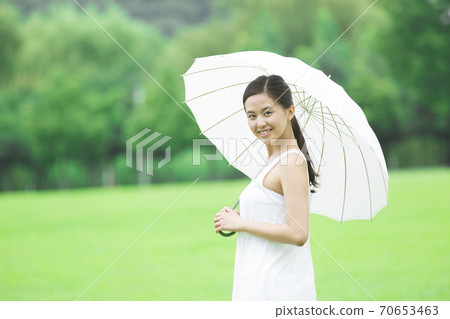 拿著遮陽傘的婦女 拿著遮陽傘的婦女 70653463