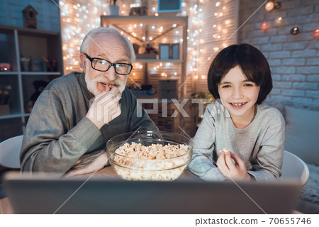 Boy with grandfather watching night movies. 70655746