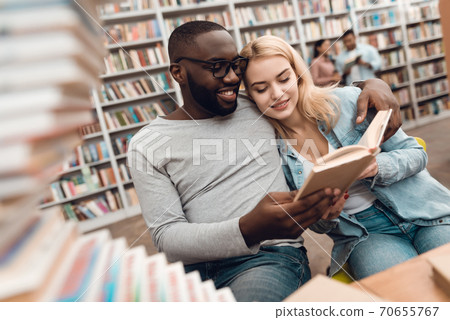A man with glasses hugged a girl in the library. A man with glasses hugged a girl in the library. 70655767