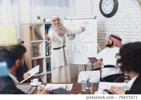 A woman in a hijab stands with a smile in office. A woman in a hijab stands with a smile in office. 70655871