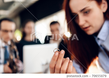 A tired woman sits and holds a ring. A tired woman sits and holds a ring. 70655879