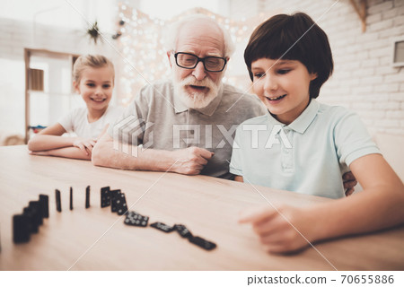 Grandpa and children are playing with dominoes. Grandpa and children are playing with dominoes. 70655886