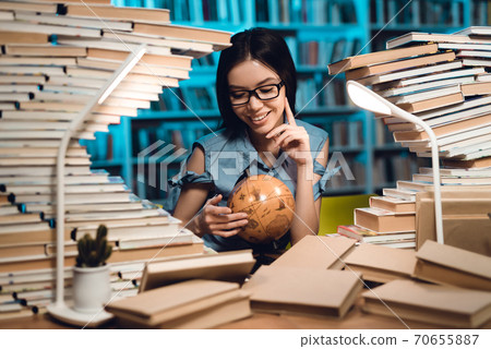 Girl looks at the globe while sitting at a table. Girl looks at the globe while sitting at a table. 70655887