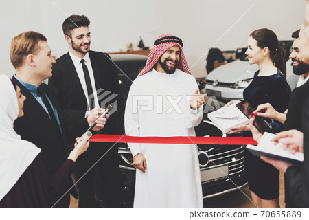 A man smiles while standing at a car dealership. A man smiles while standing at a car dealership. 70655889