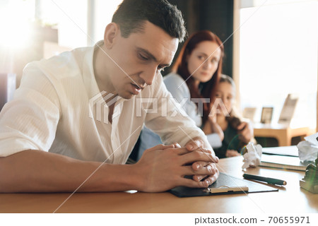 Stunned man, with folded arms, sits at table. Stunned man, with folded arms, sits at table. 70655971