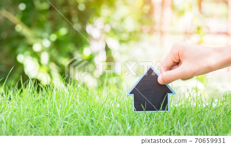 Man's hand is putting the house on the grass. Man's hand is putting the house on the grass. 70659931