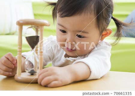 Toddler playing with an hourglass 70661335
