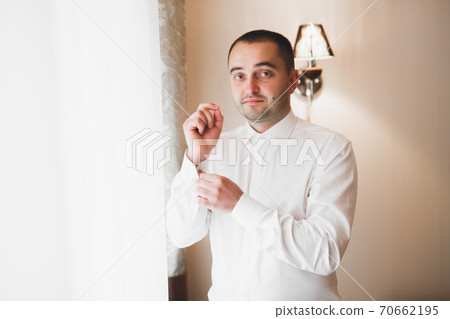 Grooms morning preparation. Handsome man getting dressed and preparing for the wedding 70662195