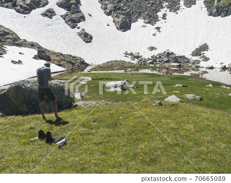 Couple of middle age hikers resting at alpine mountain meadow called Paradies with lush green grass and flowers. Stubai hiking trail, Summer Tyrol Alps, Austria Couple of middle age hikers resting at alpine mountain meadow called Paradies with lush green grass and flowers. Stubai hiking trail, Summer Tyrol Alps, Austria 70665089