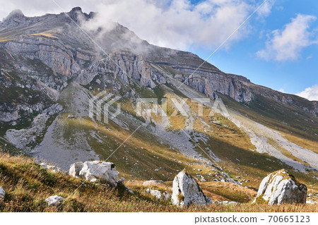 landscape with a mountain peak in the clouds and white boulders in the foreground landscape with a mountain peak in the clouds and white boulders in the foreground 70665123