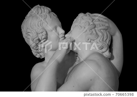 Couple of young statue are kissing, isolated on black background. Kiss marble ancient sculpture 70665398