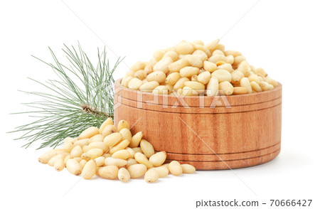 Pine nut in a wooden bowl and a pine branch on a white background. Isolated Pine nut in a wooden bowl and a pine branch on a white background. Isolated 70666427