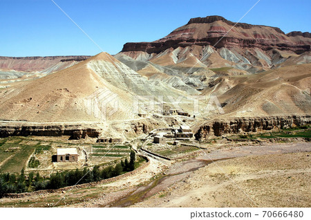 Village between Herat and Qala-e-Naw, Herat Province in Afghanistan with a backdrop of multicolored mountains in a very remote part of western Afghanistan. On the road from Herat to Bala Morgab. 70666480