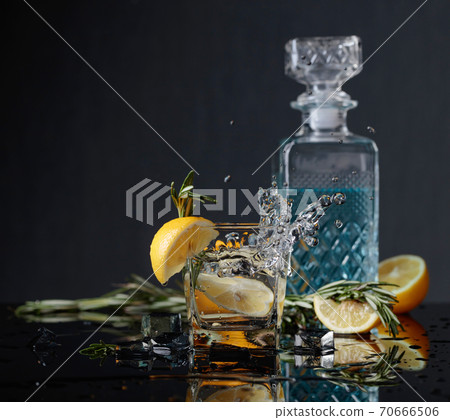 Cocktail gin-tonic with lemon slices and twigs of rosemary. Cocktail gin-tonic with lemon slices and twigs of rosemary. 70666506