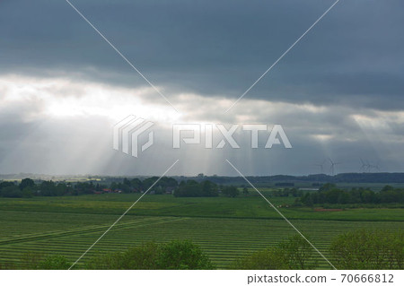 Beautiful countryside and sunrays passing through clouds on landscape with fields near Kiel - Schleswig-Holstein - Germany Beautiful countryside and sunrays passing through clouds on landscape with fields near Kiel - Schleswig-Holstein - Germany 70666812