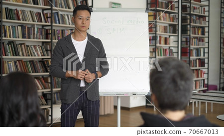 Young asian man in eyeglasses giving a lecture in the library 70667013