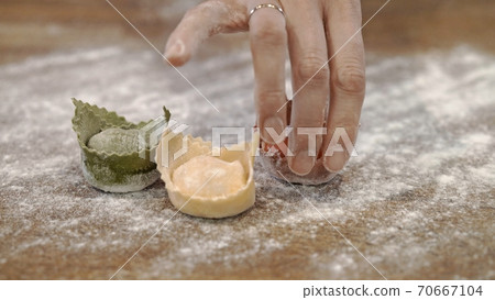 Three raw tortellini on wooden table with a hand, close up of kitchen restaurant Three raw tortellini on wooden table with a hand, close up of kitchen restaurant 70667104