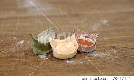 Three raw tortellini on wooden table, italian flag colours Three raw tortellini on wooden table, italian flag colours 70667105