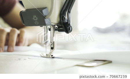 Sewing on machine, close up of hands and white cloth Sewing on machine, close up of hands and white cloth 70667239