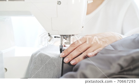 Female hands sew on a white sewing machine close-up 70667293
