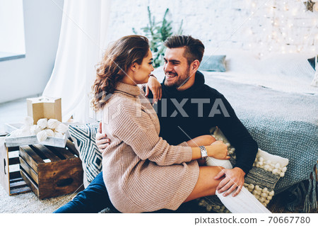 Young family dressed in knitwear looking at camera celebrating Christmas together at cozy apartments 70667780