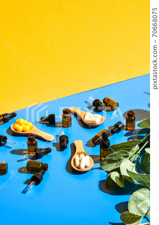 Pills on wooden spoon and dropper pipette on blue and yellow background. Hard light and shadows. Modern isometric creative minimalism concept. Vitamins and prebiotics, probiotics. Dose Pills on wooden spoon and dropper pipette on blue and yellow background. Hard light and shadows. Modern isometric creative minimalism concept. Vitamins and prebiotics, probiotics. Dose 70668075