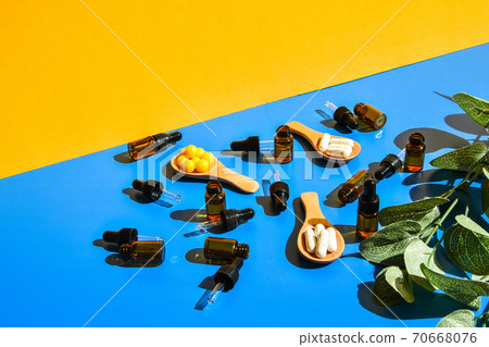 Pills on wooden spoon and dropper pipette on blue and yellow background. Hard light and shadows. Modern isometric creative minimalism concept. Vitamins and prebiotics, probiotics. Dose Pills on wooden spoon and dropper pipette on blue and yellow background. Hard light and shadows. Modern isometric creative minimalism concept. Vitamins and prebiotics, probiotics. Dose 70668076