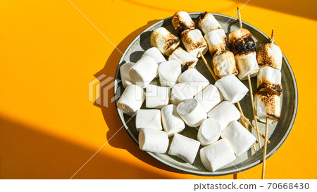 Marshmallow skewers Marshmallows On A Stick Roasting on the plate. White camping marshmallow. Creative modern background. Camping Summer Fun Concept Marshmallow skewers Marshmallows On A Stick Roasting on the plate. White camping marshmallow. Creative modern background. Camping Summer Fun Concept 70668430