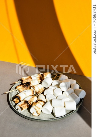 Marshmallow skewers Marshmallows On A Stick Roasting on the plate. White camping marshmallow. Creative modern background. Camping Summer Fun Concept Marshmallow skewers Marshmallows On A Stick Roasting on the plate. White camping marshmallow. Creative modern background. Camping Summer Fun Concept 70668431