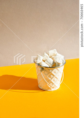 White marshmallows in metal bucket on a yellow and grey modern background, an ingredient for making a Christmas drink and decorating cakes, vertical orientation. creative food background White marshmallows in metal bucket on a yellow and grey modern background, an ingredient for making a Christmas drink and decorating cakes, vertical orientation. creative food background 70668465