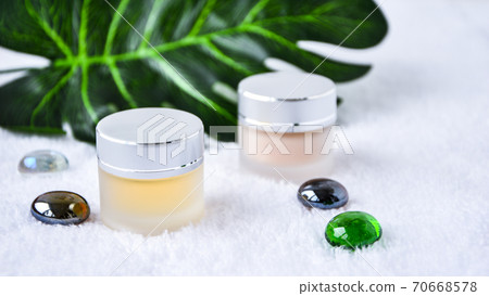 Glass jar with cream organic body care cosmetic products on monstera palm leaves over white textile background. SPA branding mock-up. 70668578