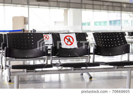 Empty waiting room at an airport during COVID-19 pandemic with social distancing signs on chairs Empty waiting room at an airport during COVID-19 pandemic with social distancing signs on chairs 70668605