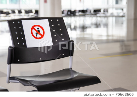 Empty waiting room at an airport during COVID-19 pandemic with social distancing signs on chairs 70668606