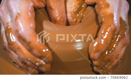 Male hands at working with clay in workshop. Male hands at working with clay in workshop. 70669062