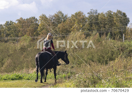 Girl on a black horse at the edge of the forest. Girl on a black horse at the edge of the forest. 70670429