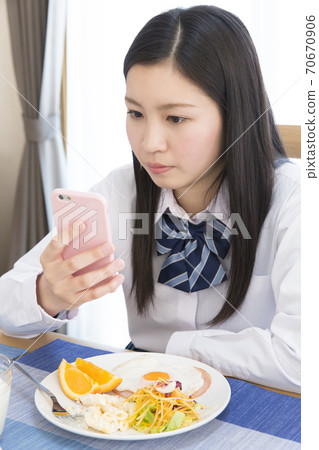 Girl looking at a smartphone while eating 70670906