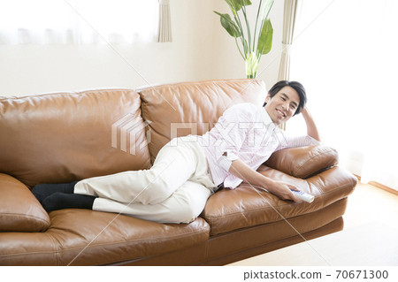 A man lying down and watching TV 70671300