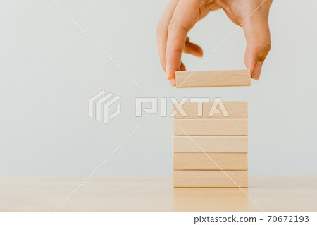 Hand arranging wood block stacking on top with wooden table 70672193