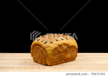 Homamade whole wheat bread loaf with pumkin seeds in black background. Homamade whole wheat bread loaf with pumkin seeds in black background. 70672391